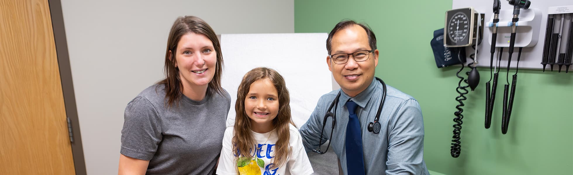 A mother and daughter smiling with a HealthSource of Ohio clinician in an exam room